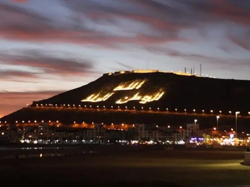 Night view of the illuminated Agadir mountain with Arabic writing and city lights, showing the peaceful evening atmosphere for those wondering is Agadir safe for solo female travellers at night