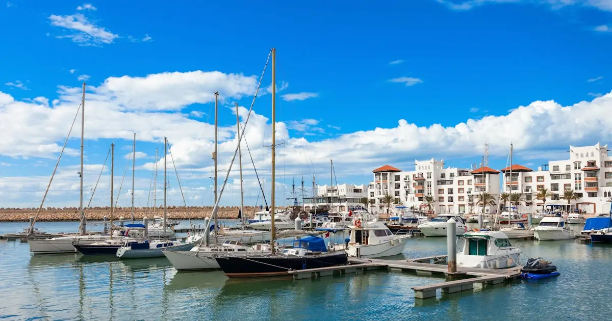 Scenic view of luxury yachts and white buildings at the Agadir Marina during the day, one of the safest areas for solo female travellers in Morocco.